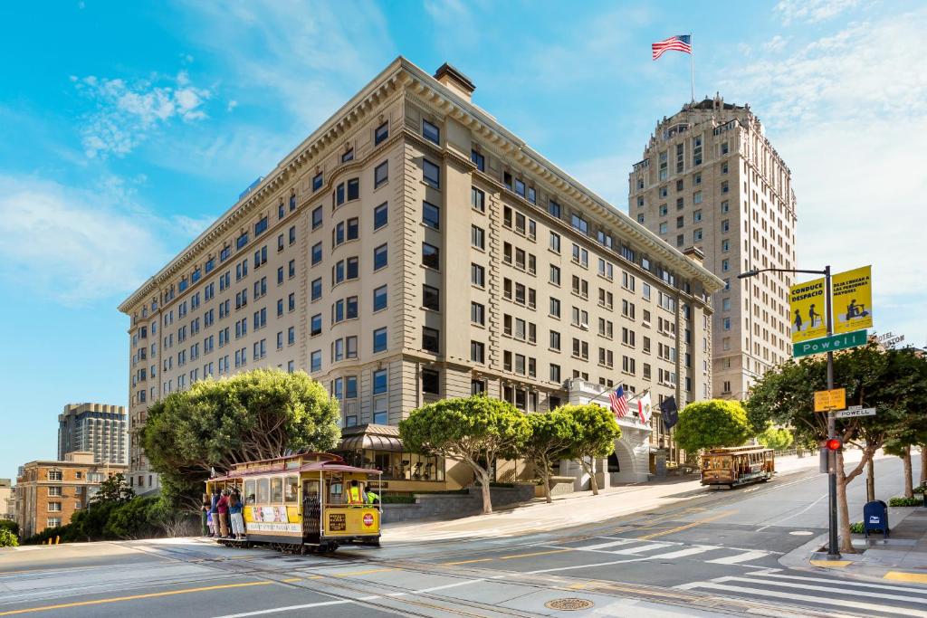 een gele trolley die langs een hoog gebouw rijdt bij Stanford Court San Francisco in San Francisco