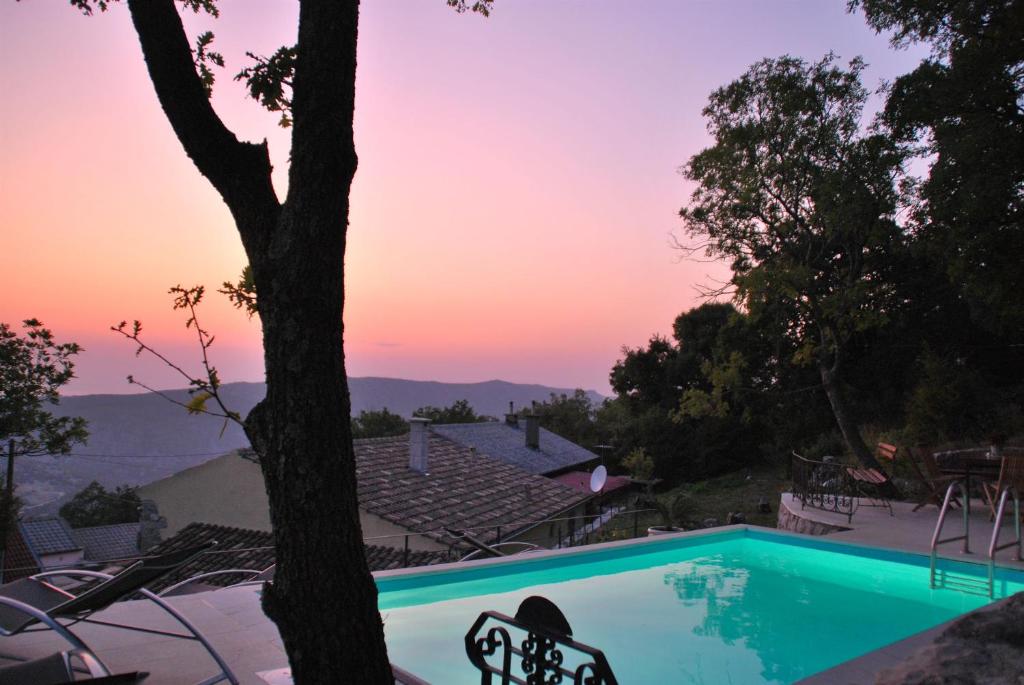 a swimming pool with a sunset in the background at House Casa Rustica in Grižane