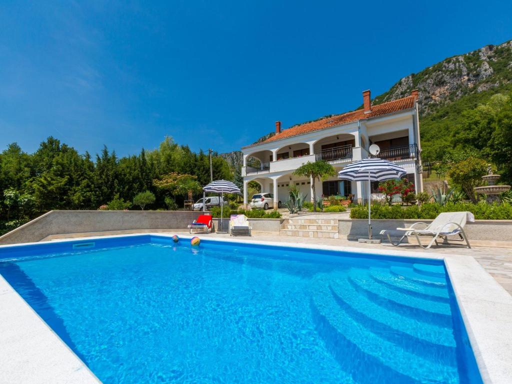 a villa with a swimming pool in front of a house at Apartment Agava in Bribir