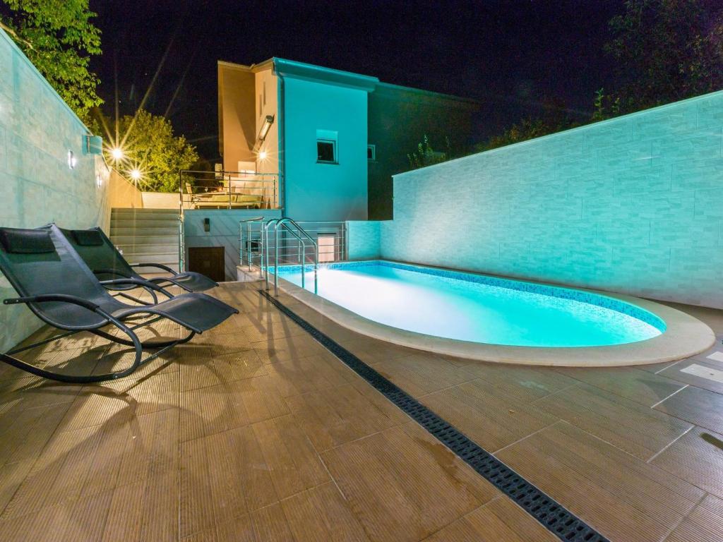 a swimming pool with chairs next to a wall at Apartments Alin in Dramalj