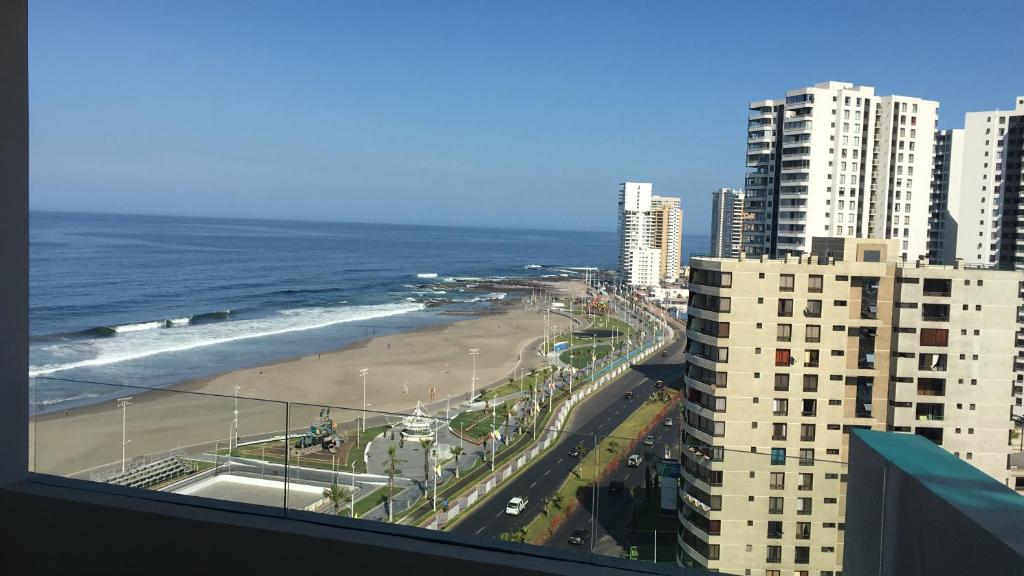 uma vista para a praia e para o oceano a partir de um edifício em Departamento Suite en Boulevard del Mar em Iquique