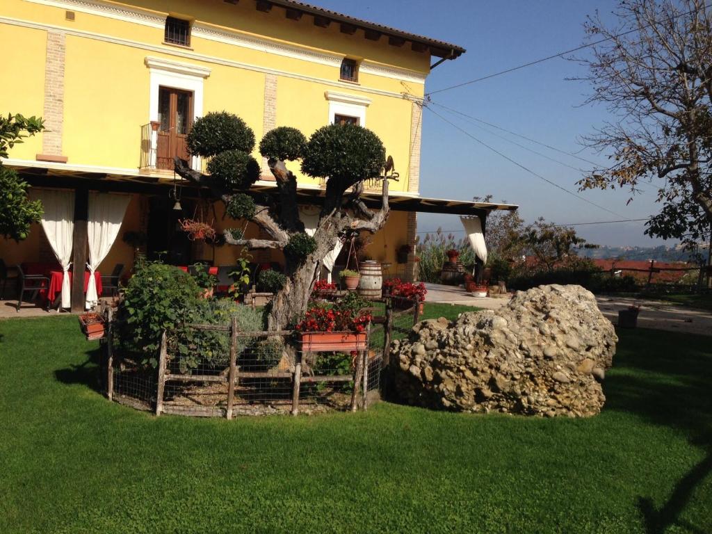 a house with a tree and flowers in a yard at Agriturismo La Rosa Dei Venti in Lanciano