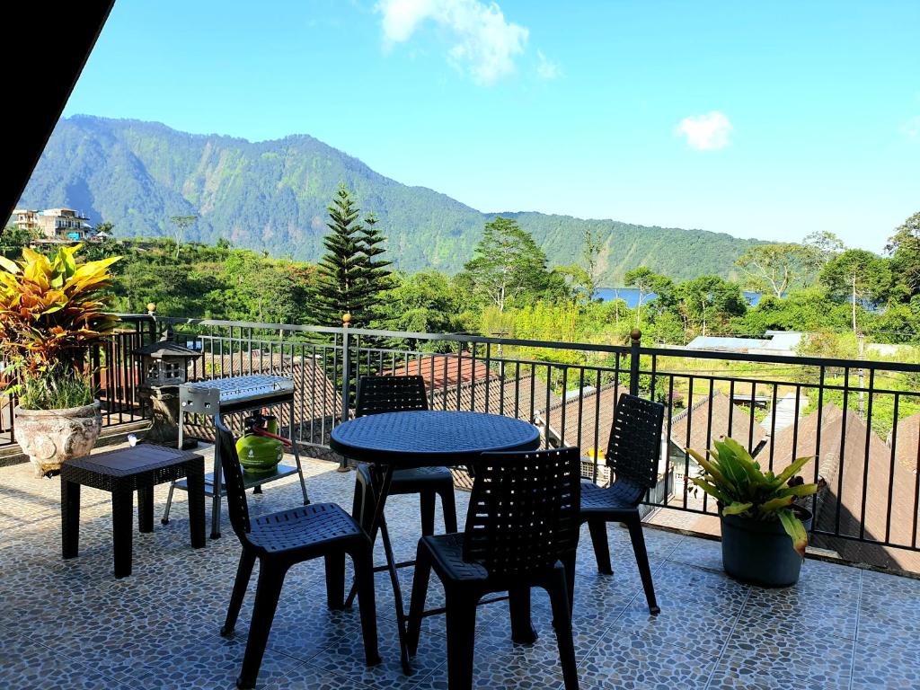 a patio with tables and chairs on a balcony with mountains at Bedugul Lake View Residence Unit B-6 in Bedugul