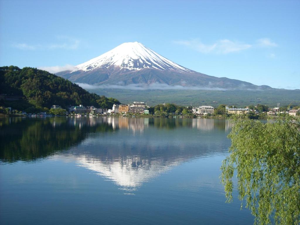 a mountain reflection in a lake with a town and buildings at Tominoko Hotel in Fujikawaguchiko