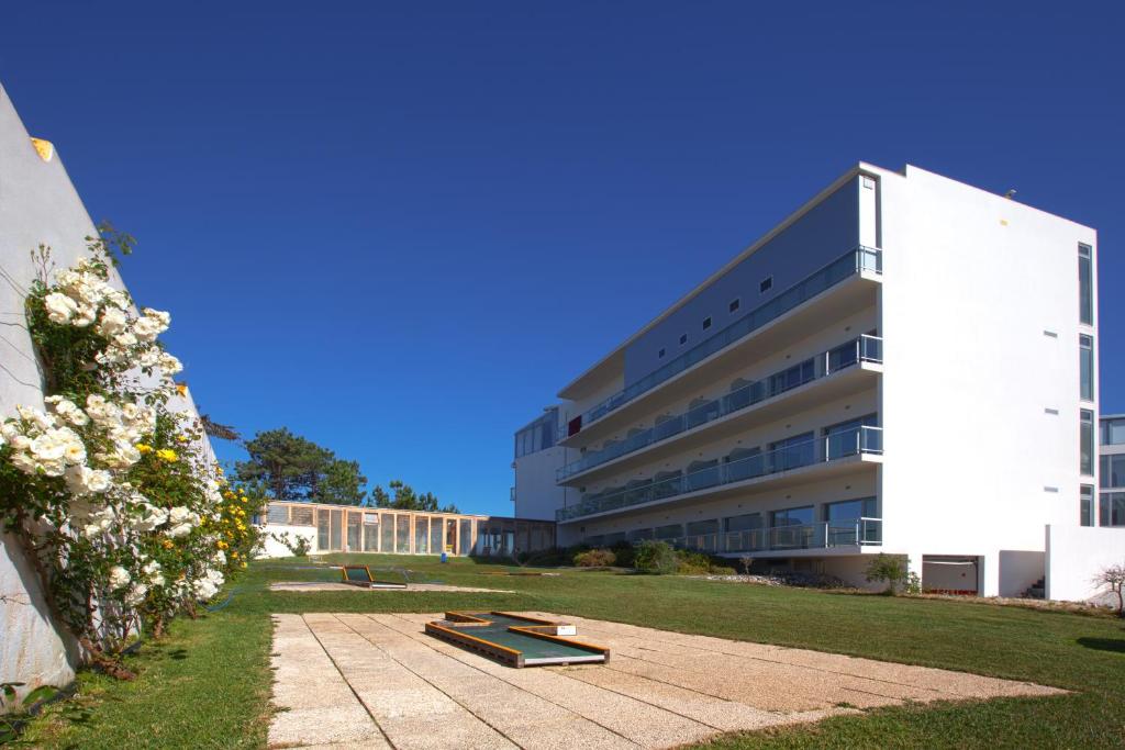 een groot wit gebouw met een skatepark ervoor bij Hotel Miramar Sul in Nazaré