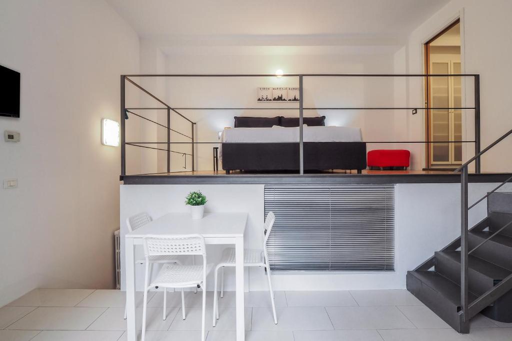 Cette chambre comprend une table et des chaises blanches ainsi qu'un lit. dans l'établissement PrimoPiano - Acerenza Flats, à Milan