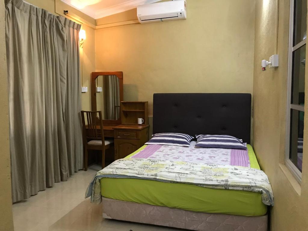 a bedroom with a bed and a table with a chair at Wan Guest House in Pasir Mas