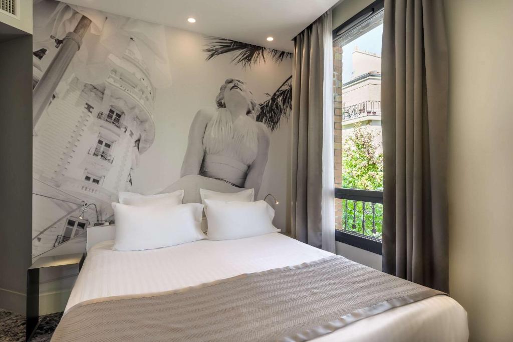 a bedroom with a bed with a poster of a woman at Hotel Sixteen Paris Montrouge in Montrouge