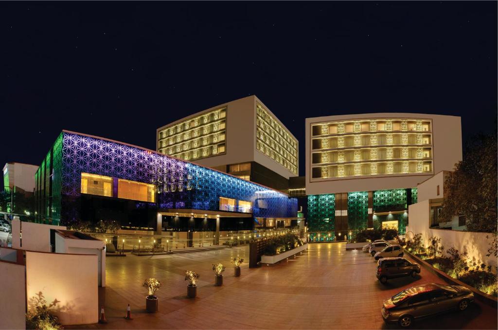 un bâtiment avec des voitures garées devant lui la nuit dans l'établissement Orange Megastructure LLP, upcoming as Le Meridien, Surat, à Surate