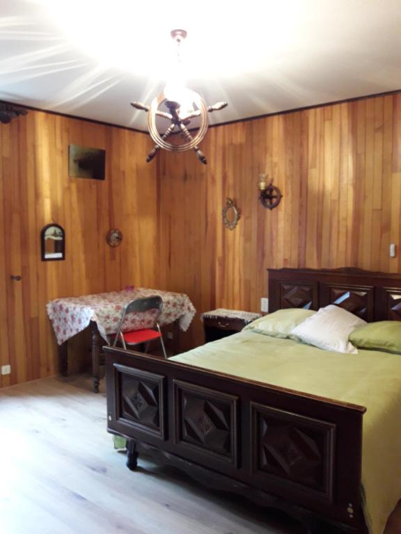 una camera con letto, tavolo e lampadario a braccio di 2 chambres d'hôtes privées louées séparément avec communs à partager a Beaufort