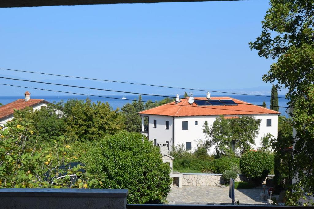 uma casa branca com um telhado laranja e árvores em Apartment Buza em Malinska