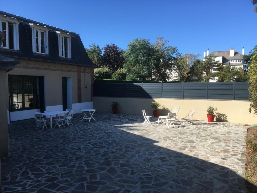 een patio met witte stoelen en een gebouw bij villa Canthar in Saint-Pair-sur-Mer