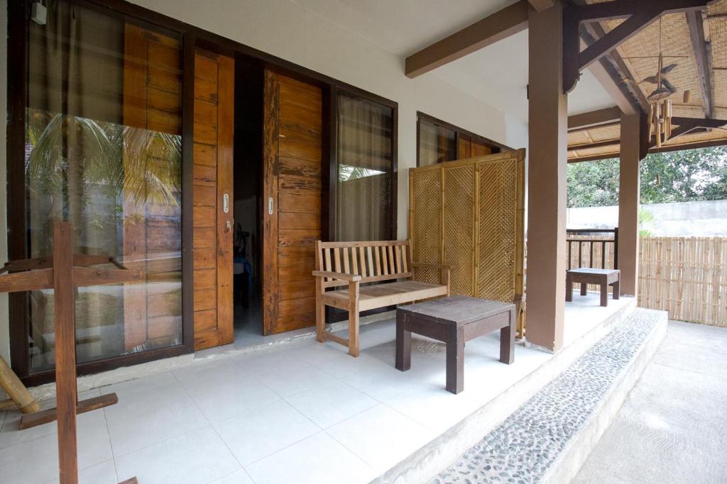 a porch of a house with a bench and windows at Asoka Homestay in Senggigi