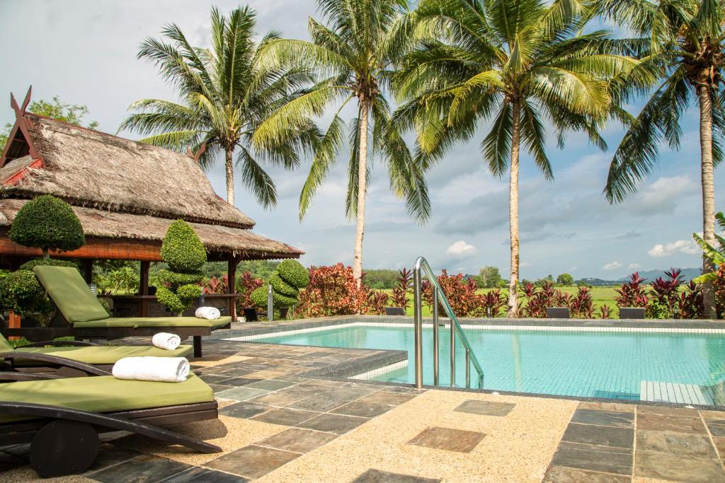 a resort swimming pool with palm trees in the background at Sunset Valley Holiday Houses in Kampung Padang Masirat