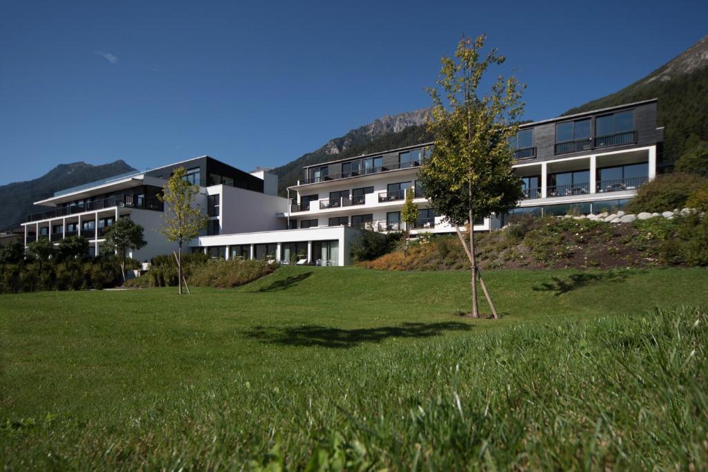 a building with a grass field in front of it at Hotel & Appartements Oberhofer in Telfes im Stubai