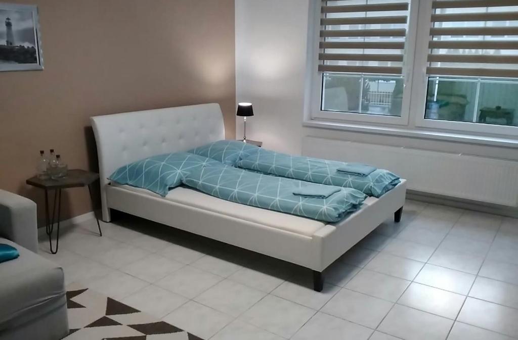 Slnečný apartmánový dom Oslany في Oslany: سرير أبيض مع لحاف أزرق في الغرفة