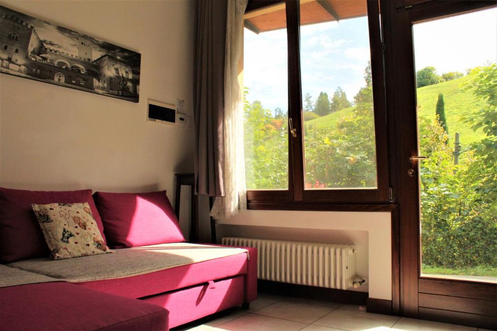 Una sala de estar con un sofá y una ventana grande. en BoscoBo - Relax & Natura, en Bolonia