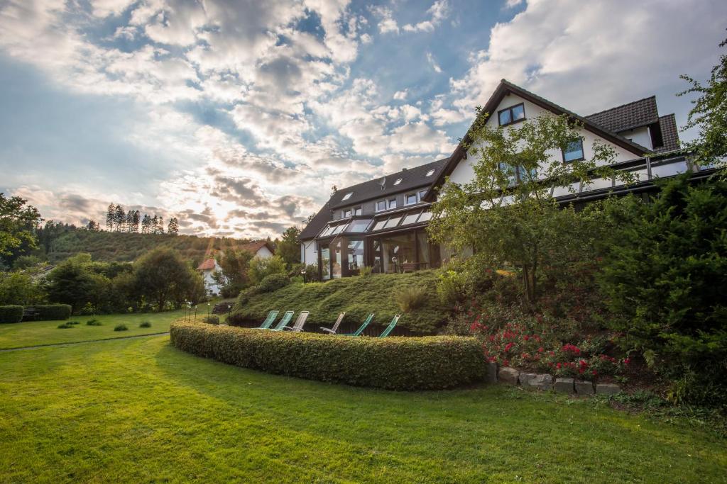 una casa en una colina con un patio de hierba en Hotel im Auerbachtal, en Bad Laasphe