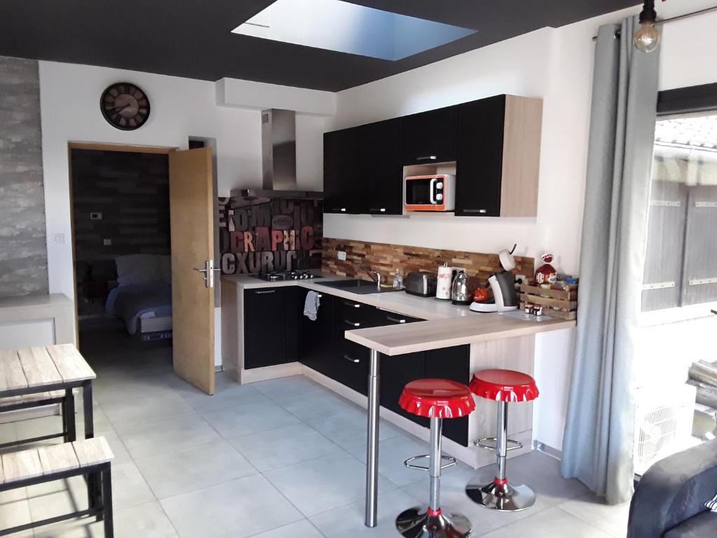 a kitchen with a counter and two red stools at Joli 2 pièces esprit loft moderne in Pau