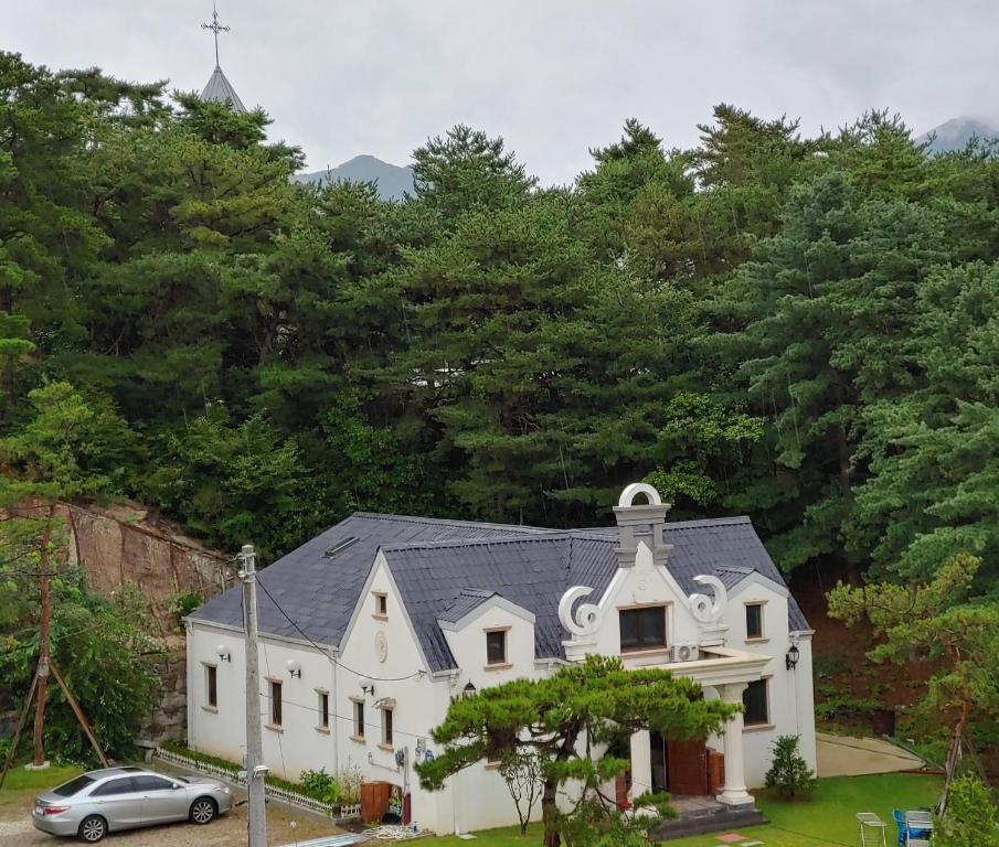 a white church with a car parked in front of it at The Castle Stay in Chuncheon