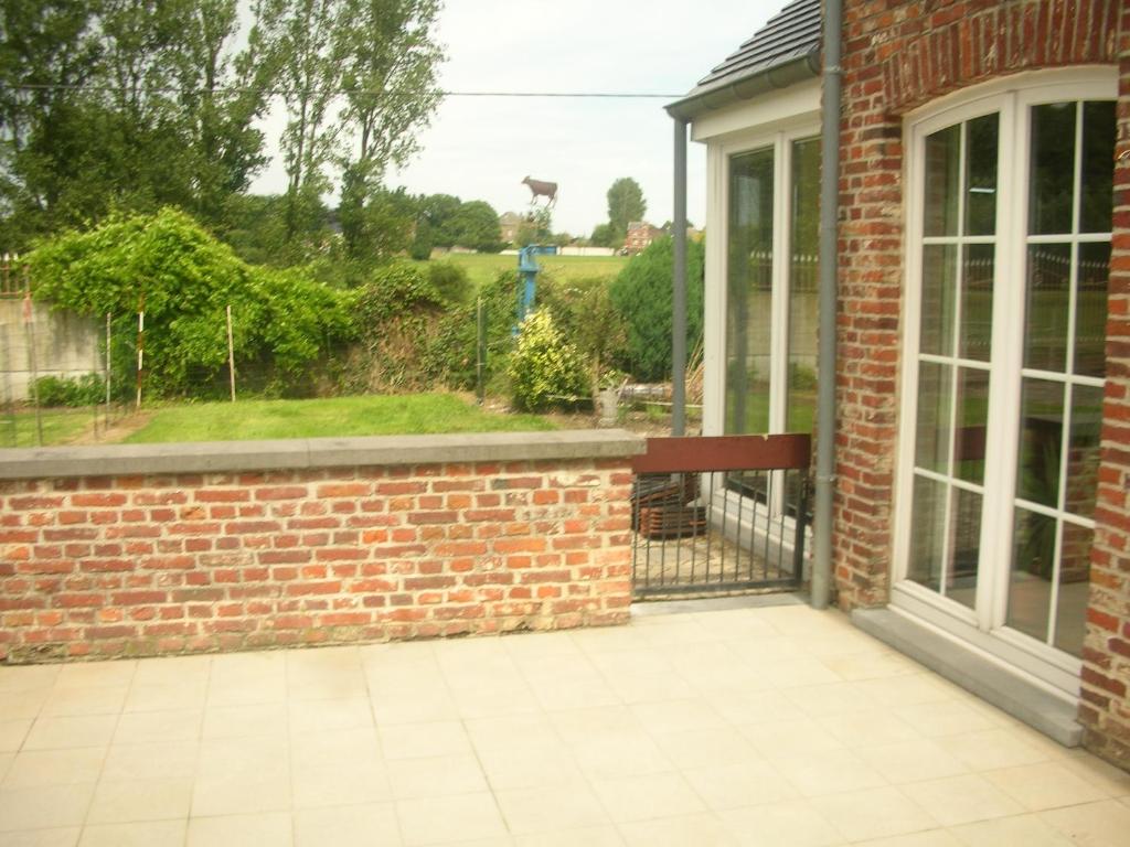 a patio with a brick wall and a window at ferme d'herlaimont 1 in Chapelle-lez-Herlaimont