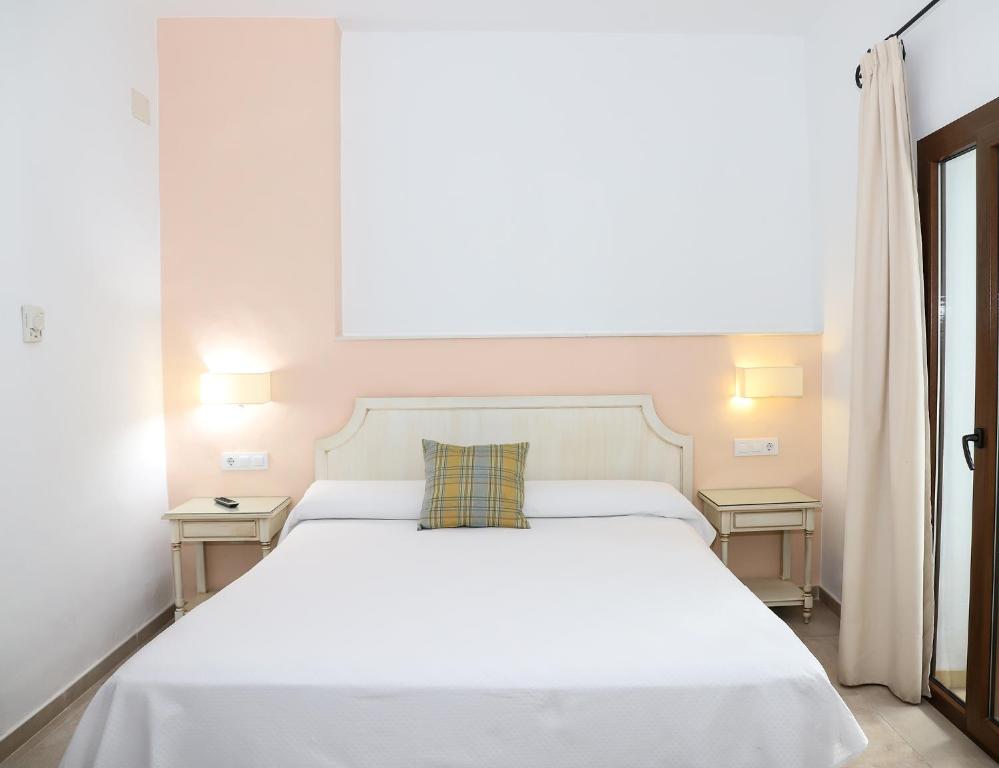 a bedroom with a white bed with two tables at Hostal Doña Lola Marina in Zahara de los Atunes
