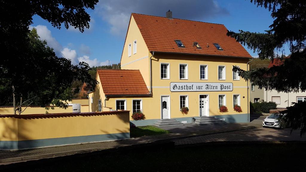 um grande edifício amarelo com um telhado vermelho em Gasthof zur Alten Post em Wimmelburg