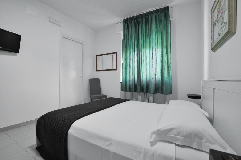 ComunanzaにあるGiorgia Tassi Affittacamereのベッドルーム(白いベッド1台、緑のカーテン付)