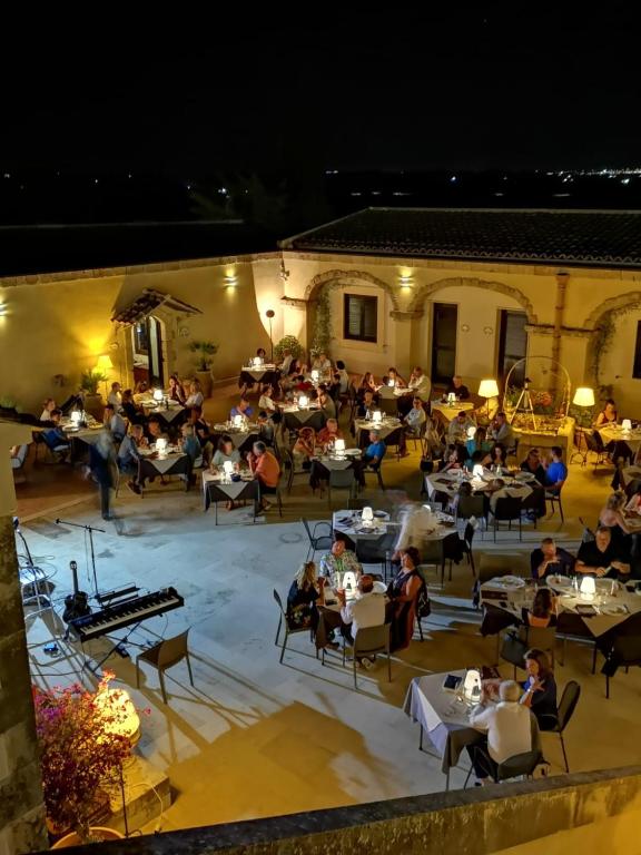 a group of people sitting at tables in a restaurant at Hotel La Corte Del Sole in Noto