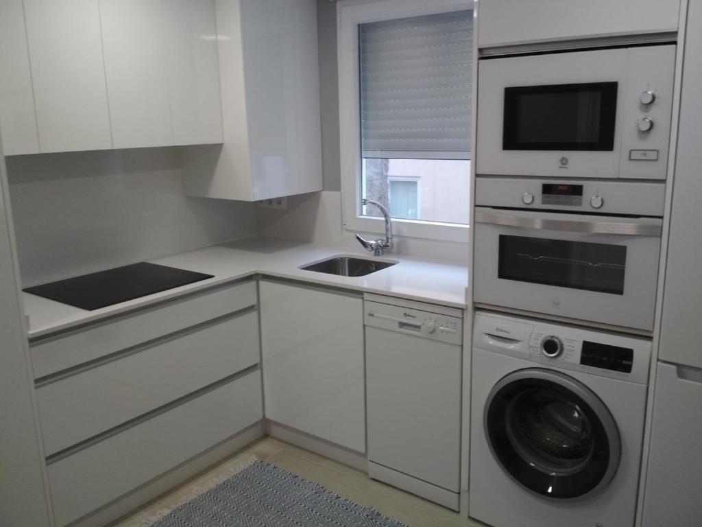 - une cuisine blanche avec un lave-linge et un évier dans l'établissement Marisol apartament, à Saint-Jacques-de-Compostelle