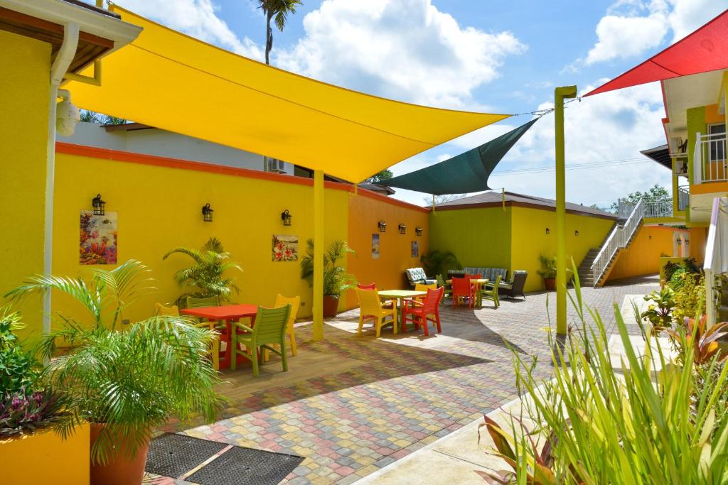 a patio with tables and chairs and a yellow building at Coco La Palm in Negril