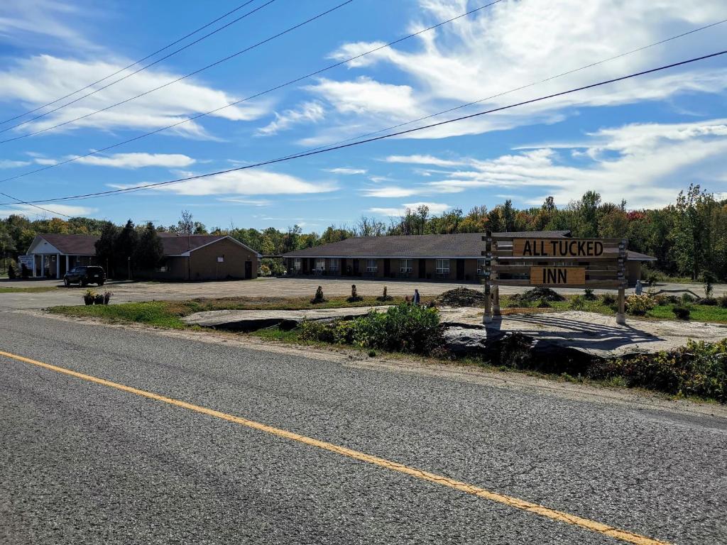 un camino vacío con un cartel delante de un edificio en All Tucked Inn, en Waubaushene