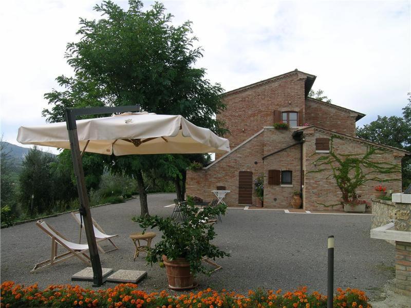 ein weißer Regenschirm und zwei Stühle und ein Haus in der Unterkunft Villa Podere S. Gaetano in Chiusi