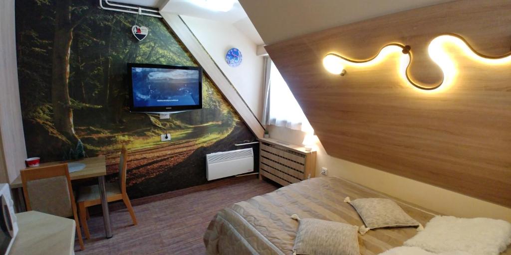 um quarto com uma cama, uma televisão e uma mesa em Elite Apartment Konaci em Kopaonik
