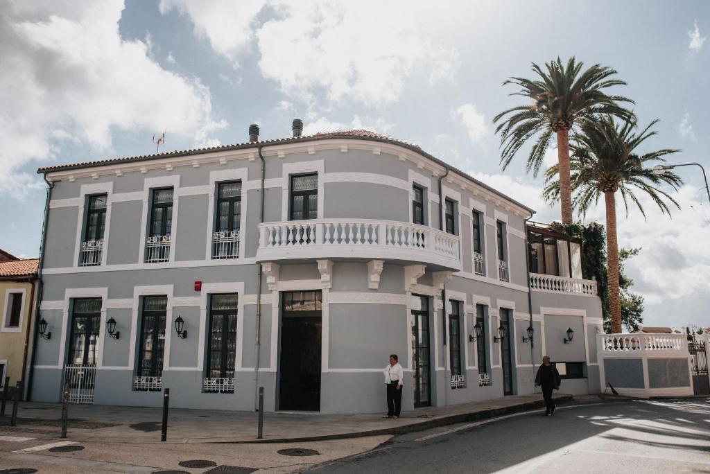 un edificio blanco con dos personas de pie delante de él en 1930 Boutique Hotel en Arzúa