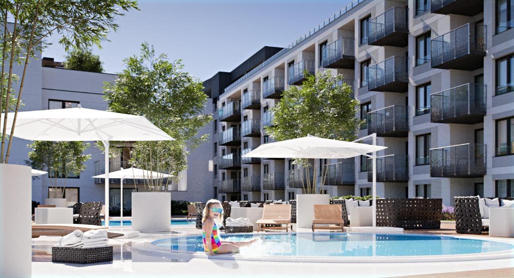 a doll sitting in a swimming pool in front of a building at Bodnar Apartamenty Nadmorskie Tarasy Port in Kołobrzeg