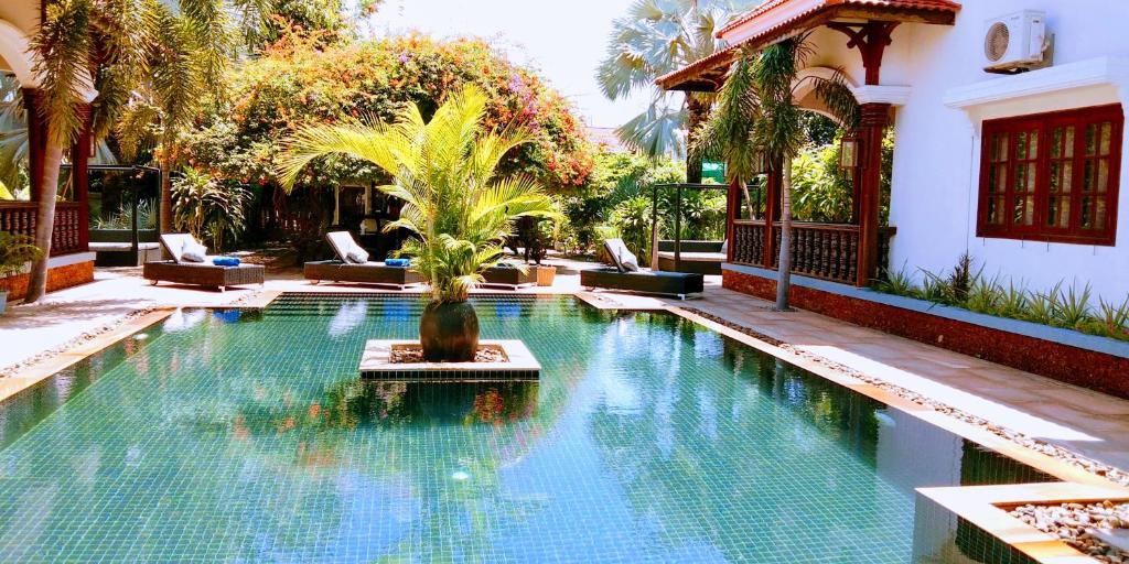 uma piscina com uma palmeira no meio em Eureka Villas Siem Reap em Siem Reap