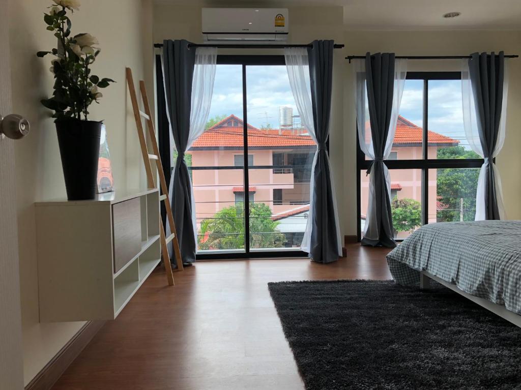 a bedroom with a large window with a view of a building at PaperPlane Haiya Nordic House in Chiang Mai
