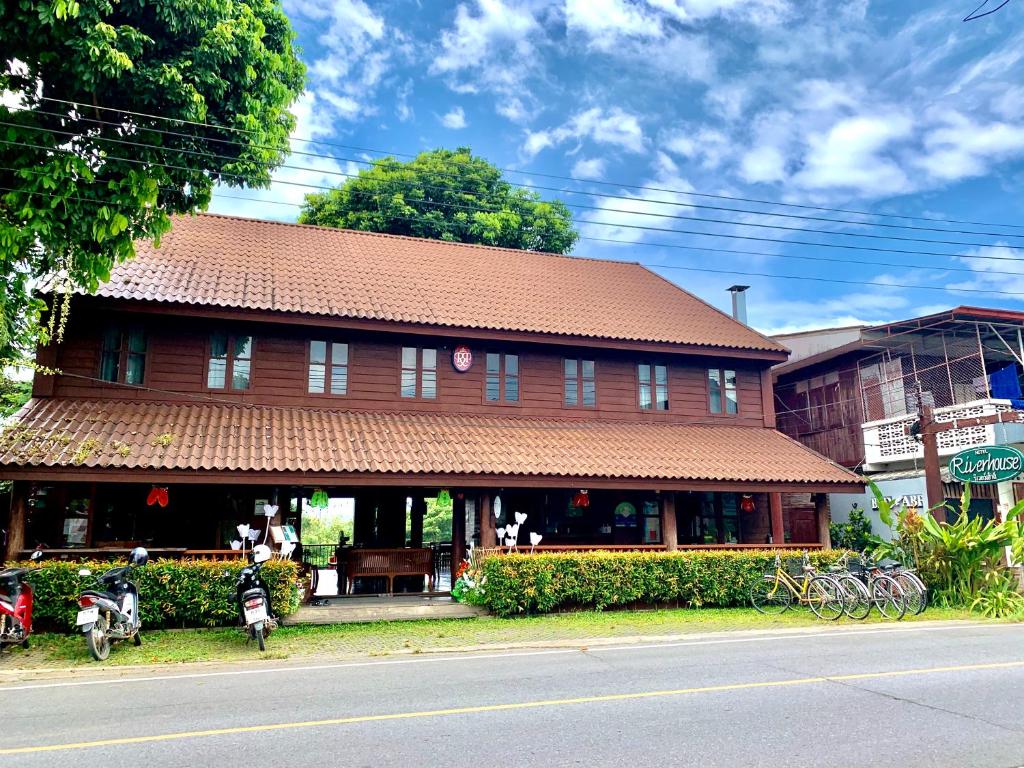 a building with a brown roof on the side of a street at Riverhouse Hotel (The Teak House) in Mae Sariang