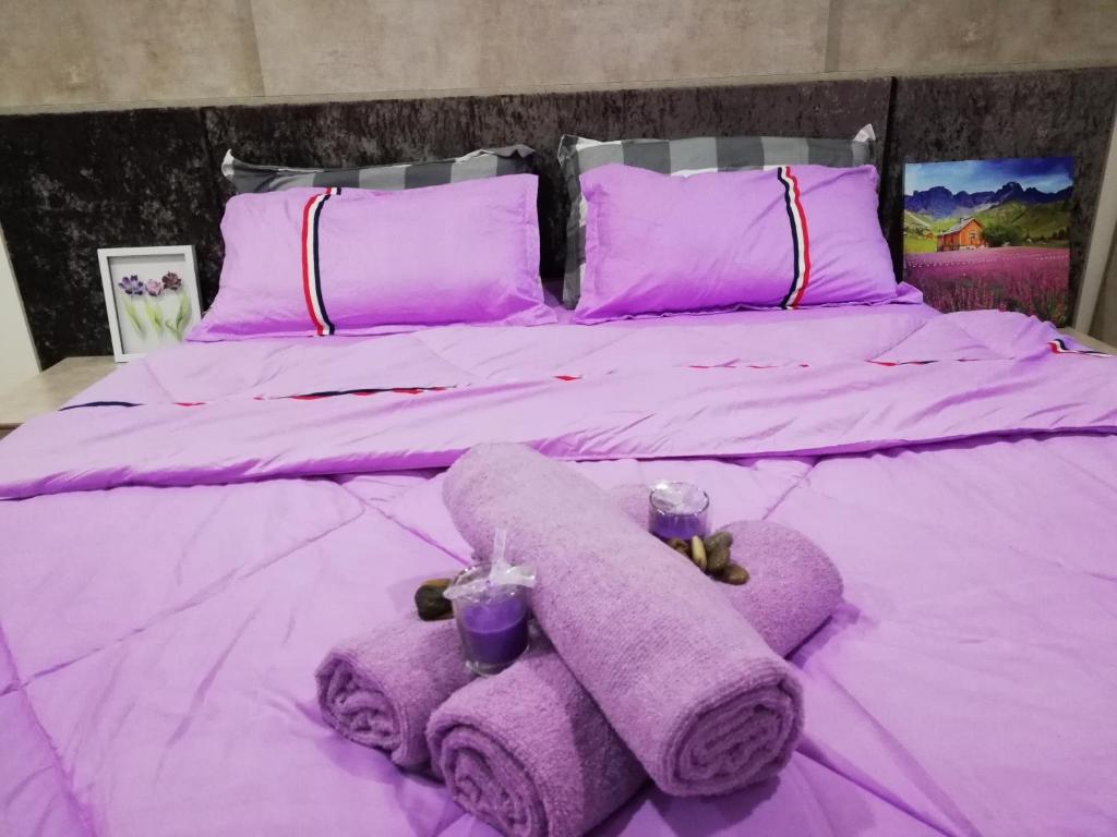 Cama morada con 2 toallas y almohadas moradas en LAVENDER Suite@I_CITY en Shah Alam