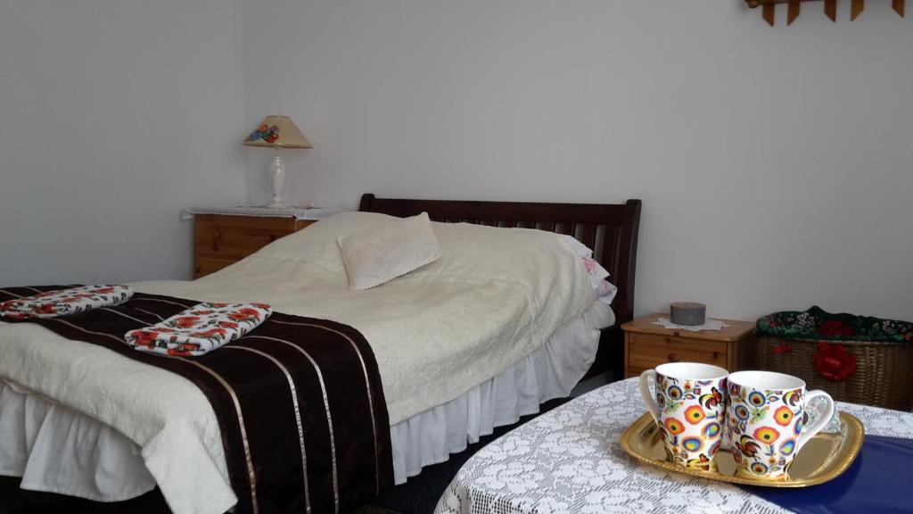 a bedroom with a bed with two cups on a table at Dom Na Ludowo w Brzeźnicy in Brzeźnica