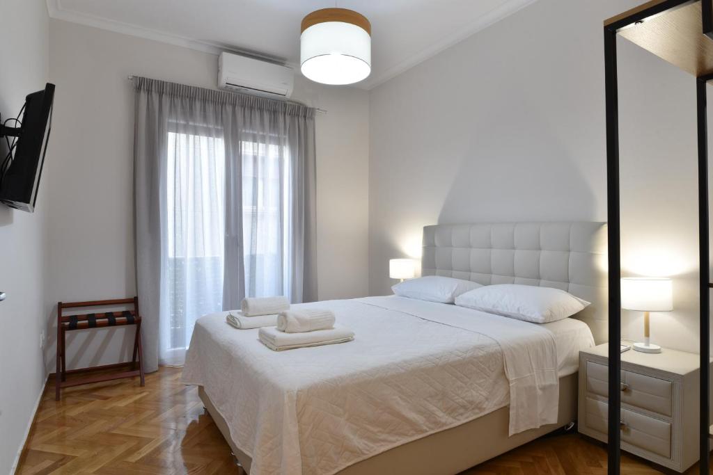 a white bedroom with a large bed with two towels on it at A&F Leisure and Business,Kolonaki Apartment in Athens