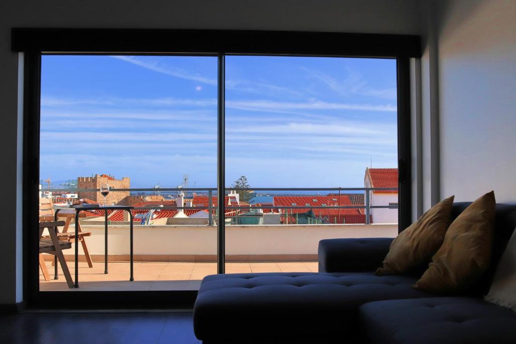 - un salon avec un canapé et une grande fenêtre dans l'établissement Castle in Blue Apartments-Sea View, à Sines