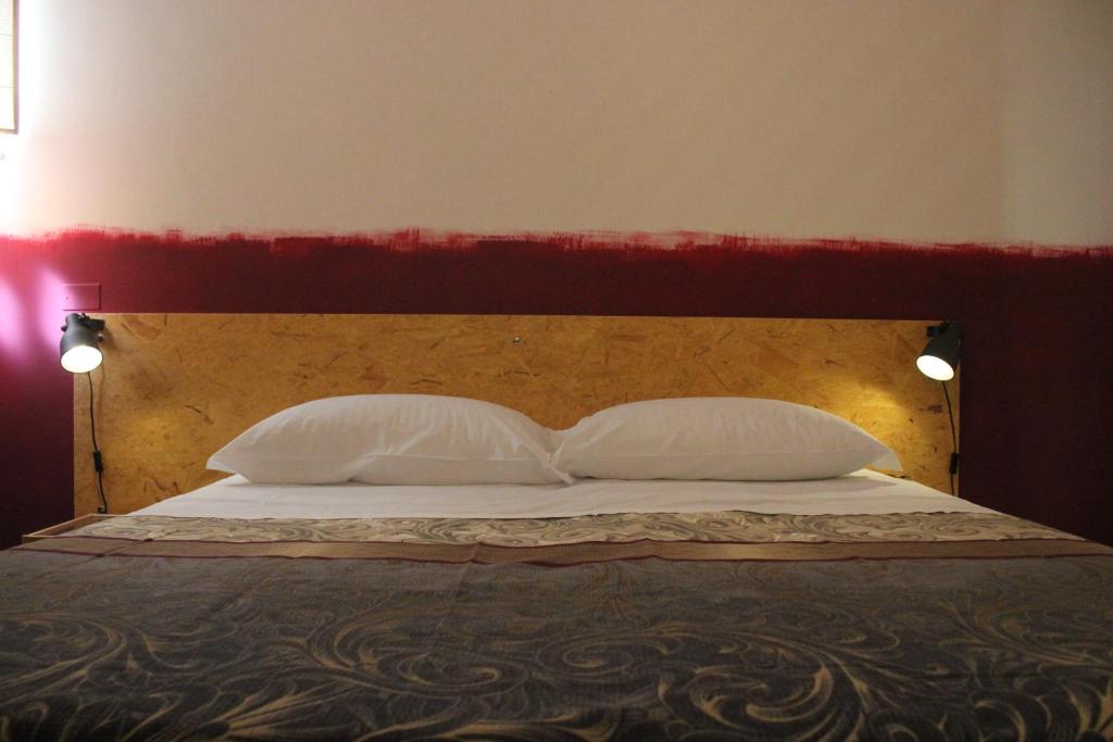 1 cama con 2 almohadas blancas y cabecero rojo en Casa Madè, en Chieti