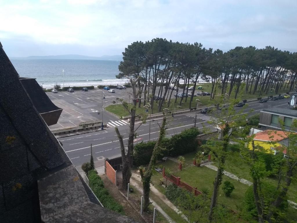 vistas a una calle con aparcamiento y al océano en Apartamento primera línea playa d samil, en Vigo