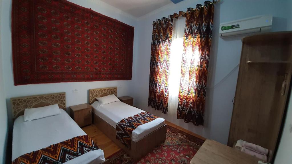 a small room with two beds and a window at "YOQUT HOUSE" guest house in the centre of ancient city in Khiva