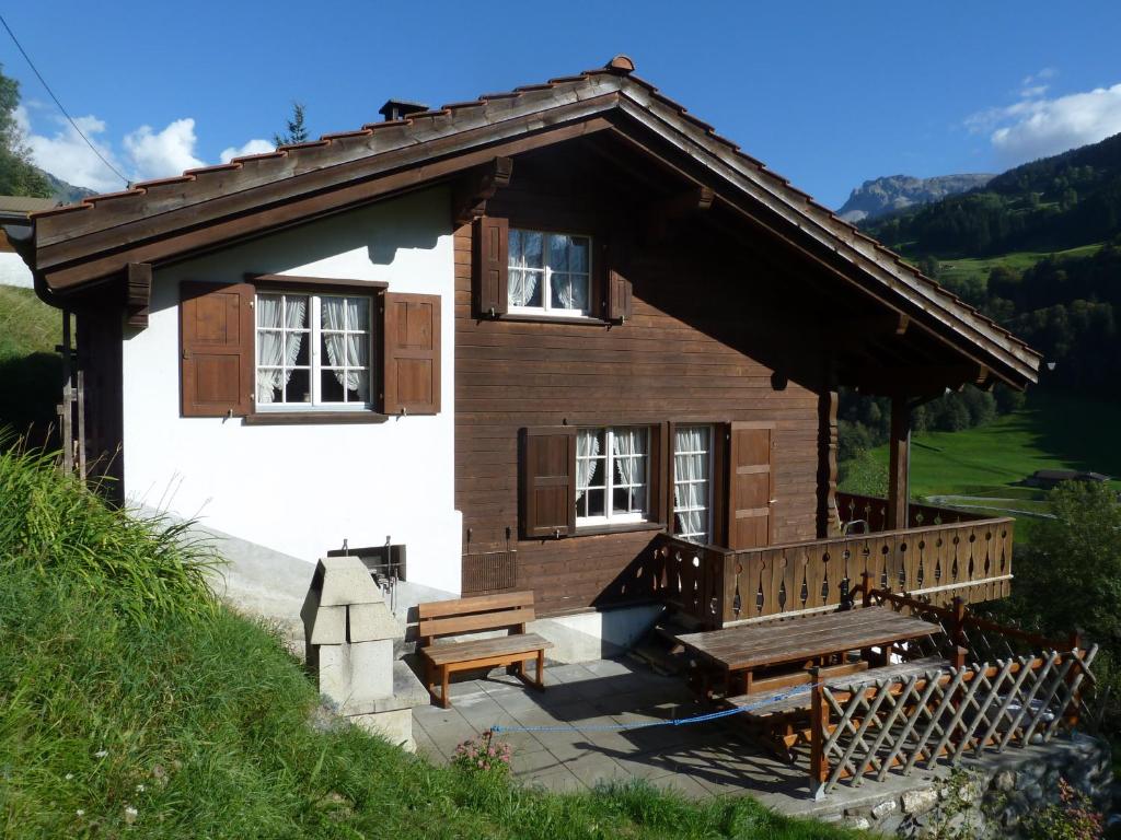 una pequeña casa con un banco y una mesa de picnic en Ferienhaus Stutz links en Küblis
