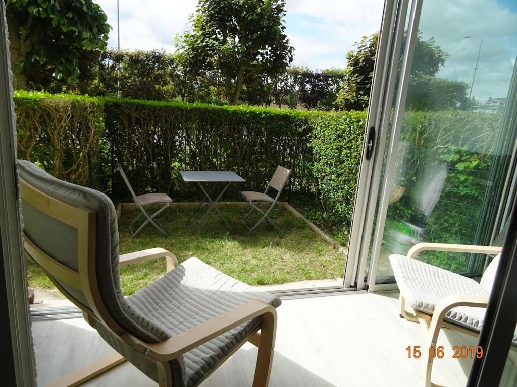 un patio con 2 sillas, una mesa y una ventana en Charmant 2 pièces à 500 m des plages et du centre, en Cabourg