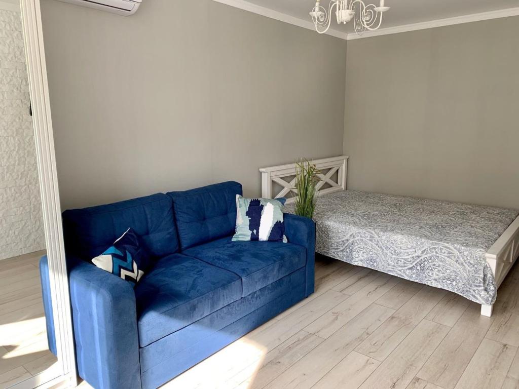 Sofá azul en la sala de estar con cama en Sisters apartment en Chernihiv