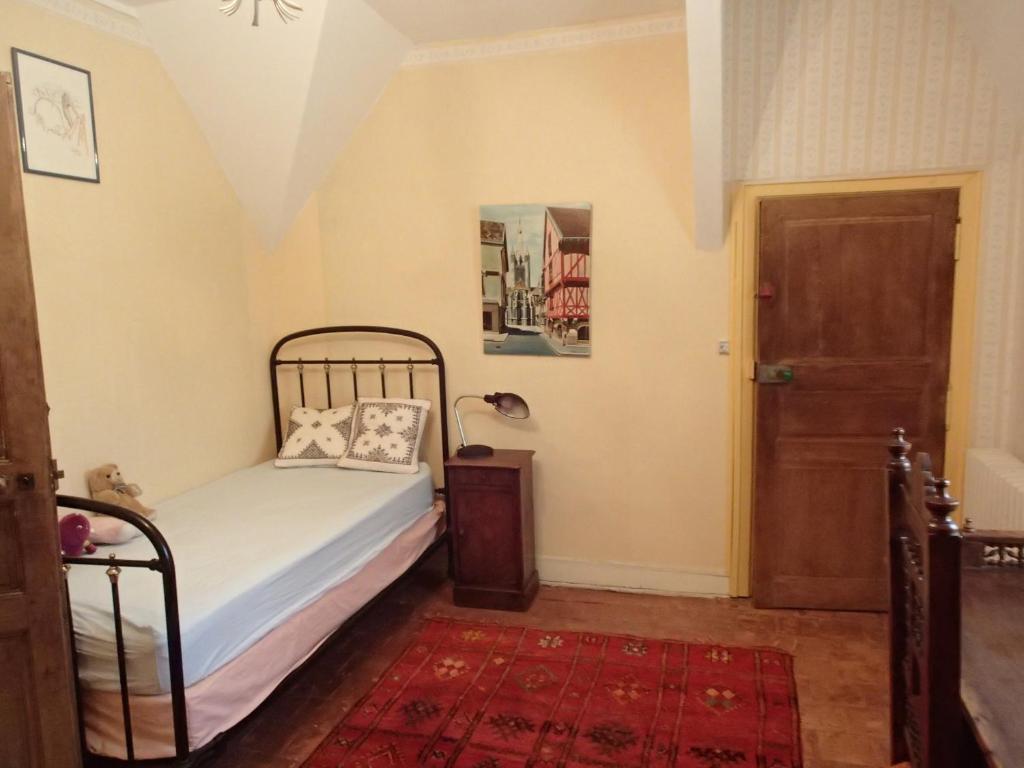 a bedroom with a bed and a door and a rug at France Petit Château in Loué